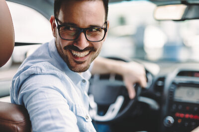 Auto verkaufen in der Nähe FAQ Ein Man sitzt im Auto und hat Fragen rund um den Autoverkauf in der Nähe.